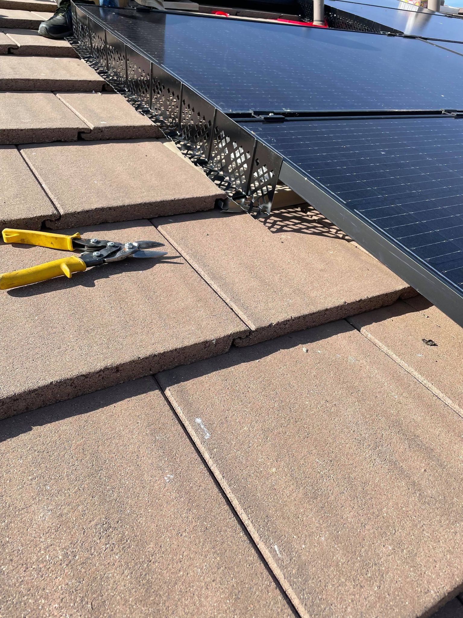 Solar panels installed on a tiled roof with tools nearby.