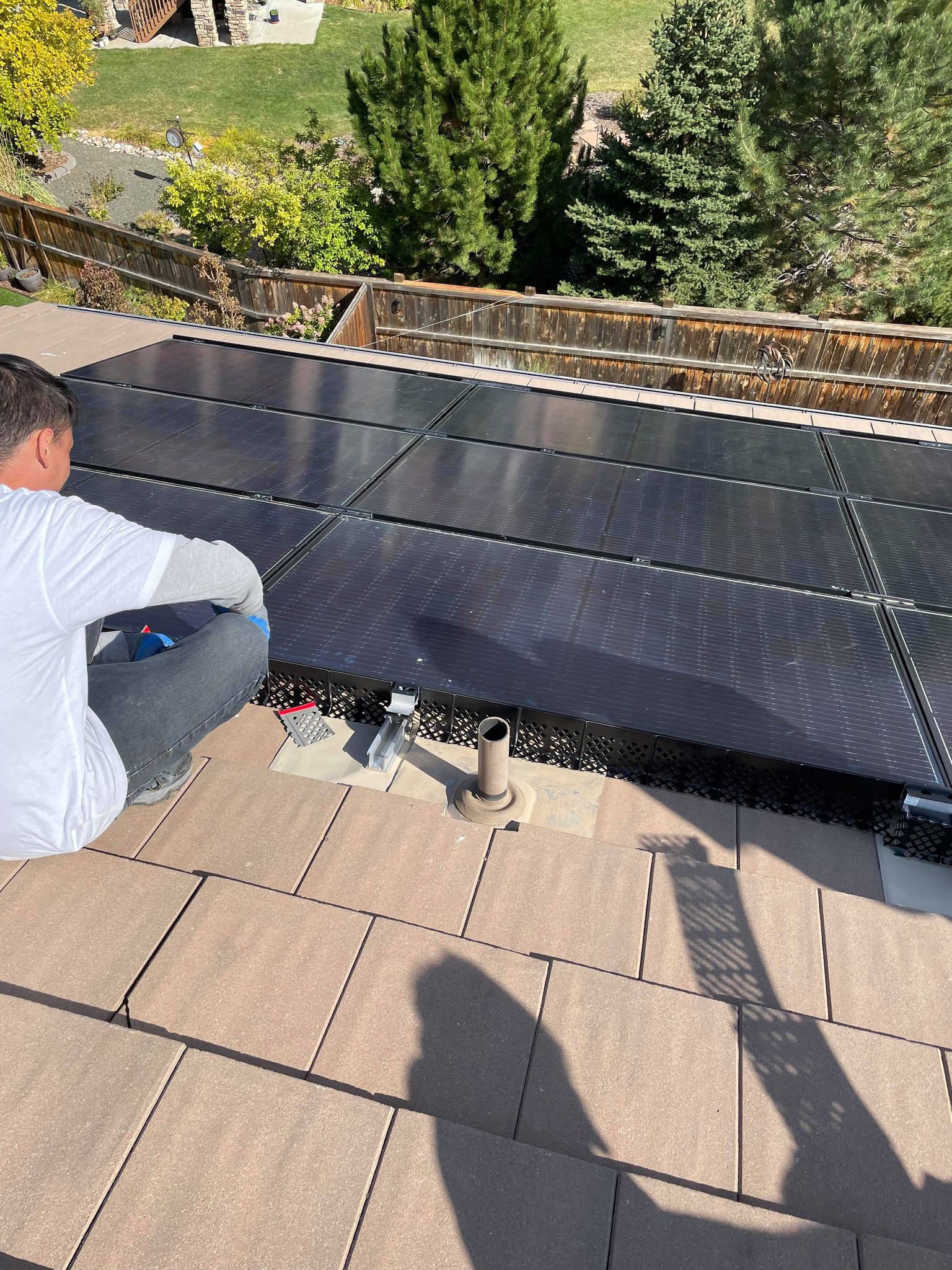 A man is installing solar panels on the roof of a house.