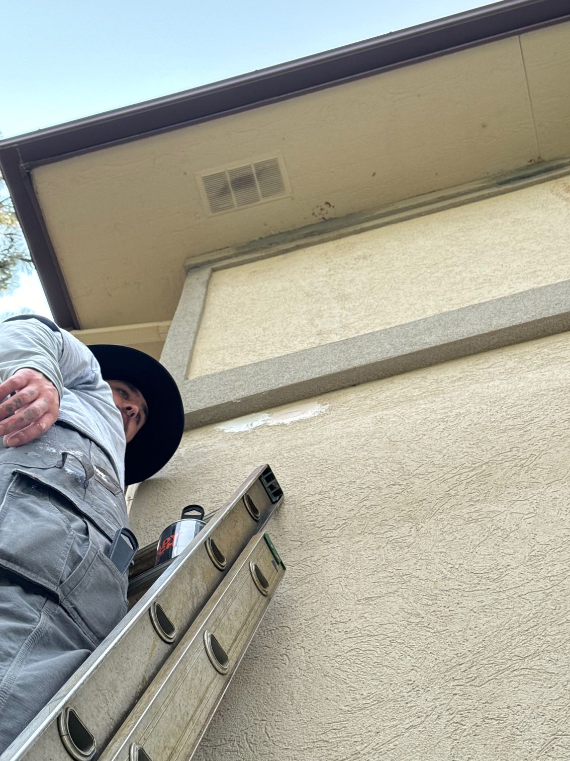 A man is standing on a ladder next to a building.