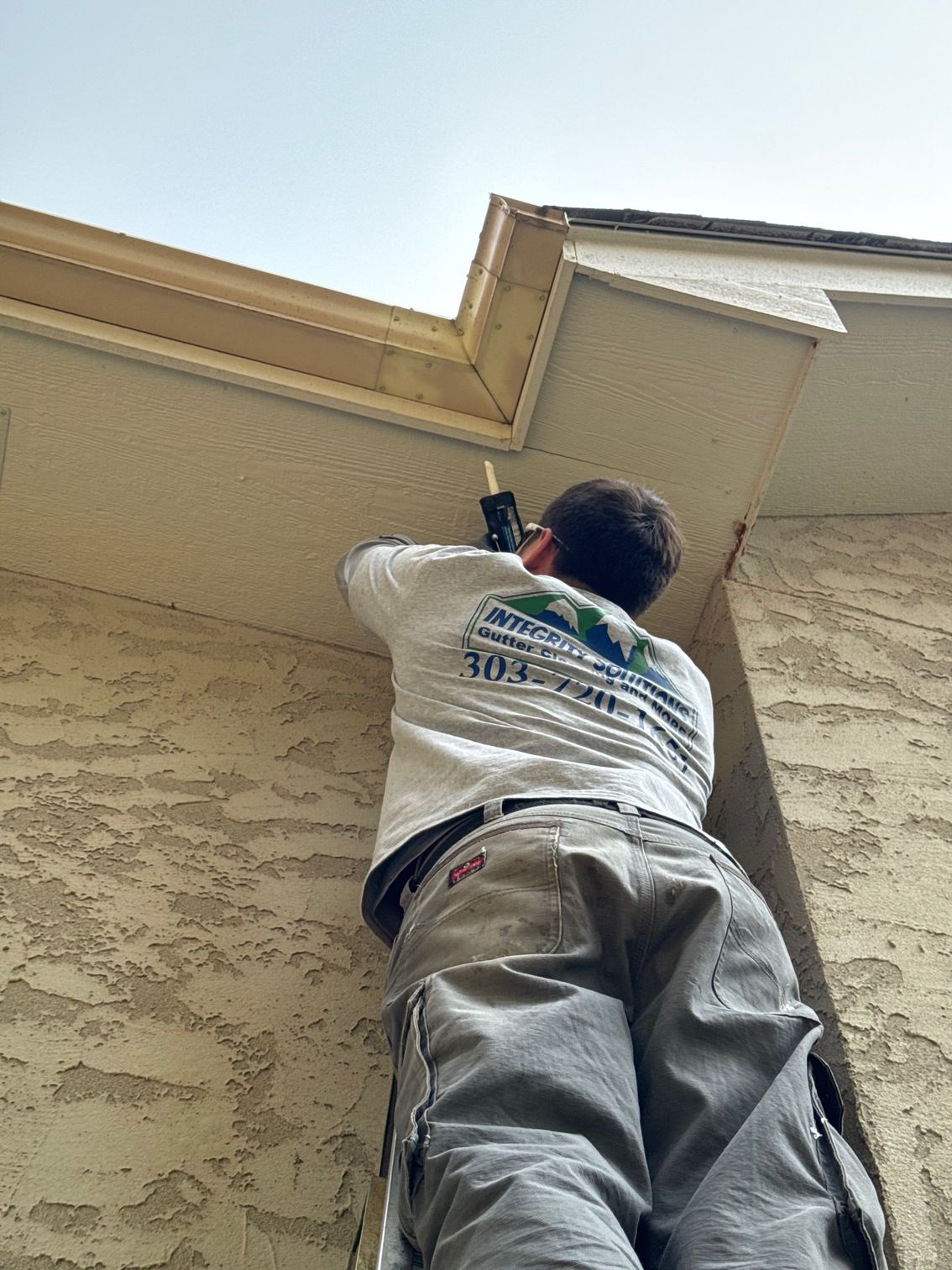 A man is standing on a ladder on the side of a building.