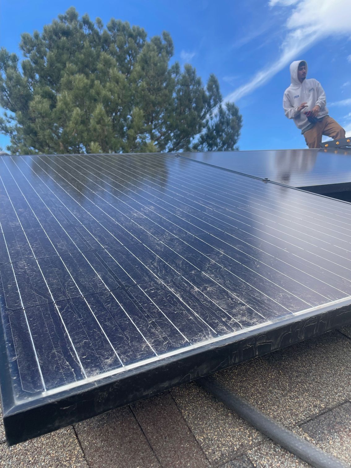 A man is standing on top of a roof with solar panels.
