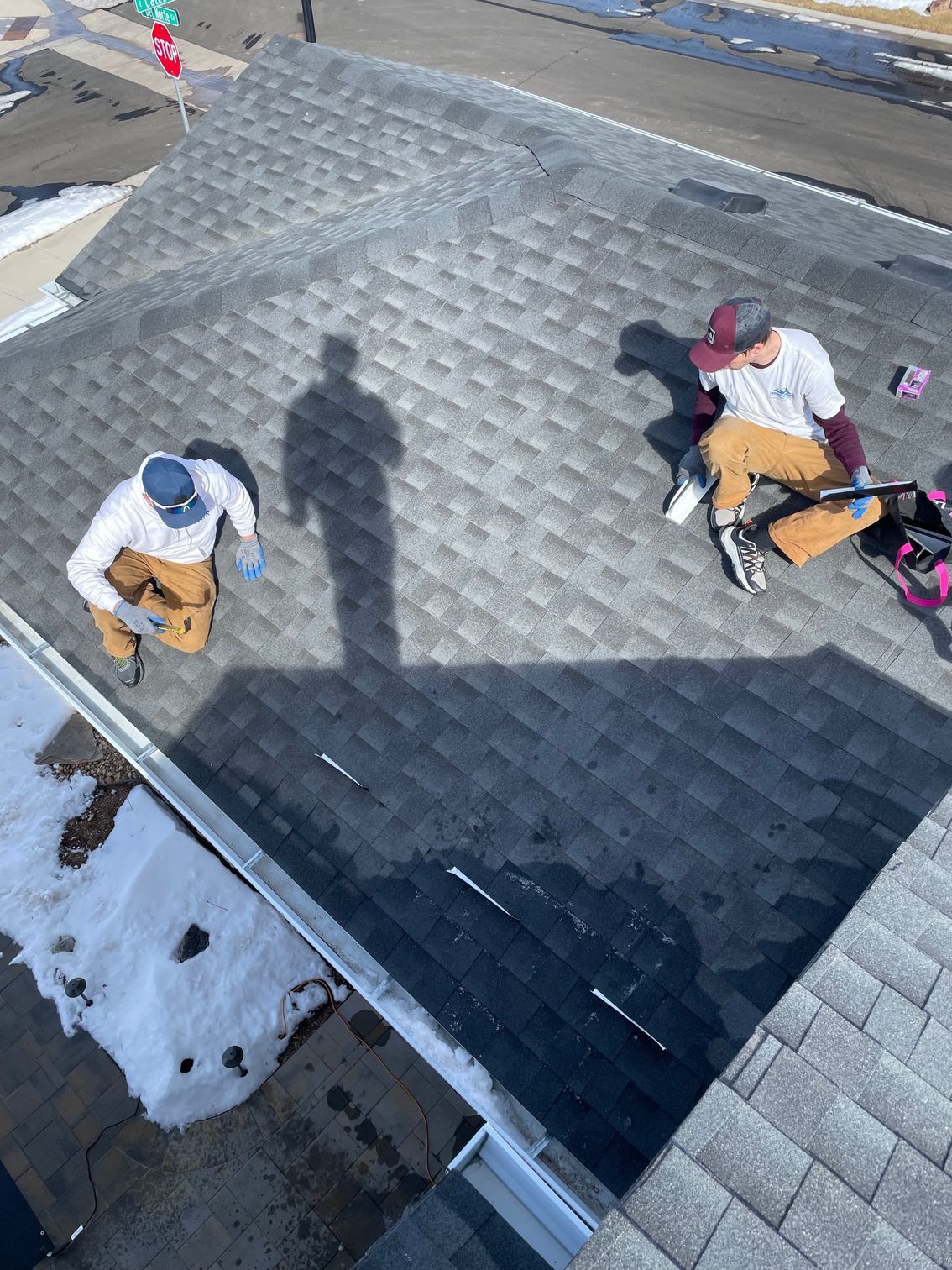 Two men are working on the roof of a house.
