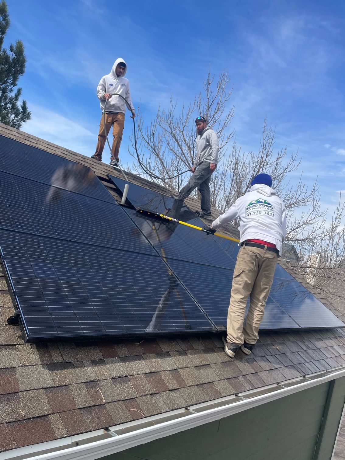 Two men are installing solar panels on the roof of a house.
