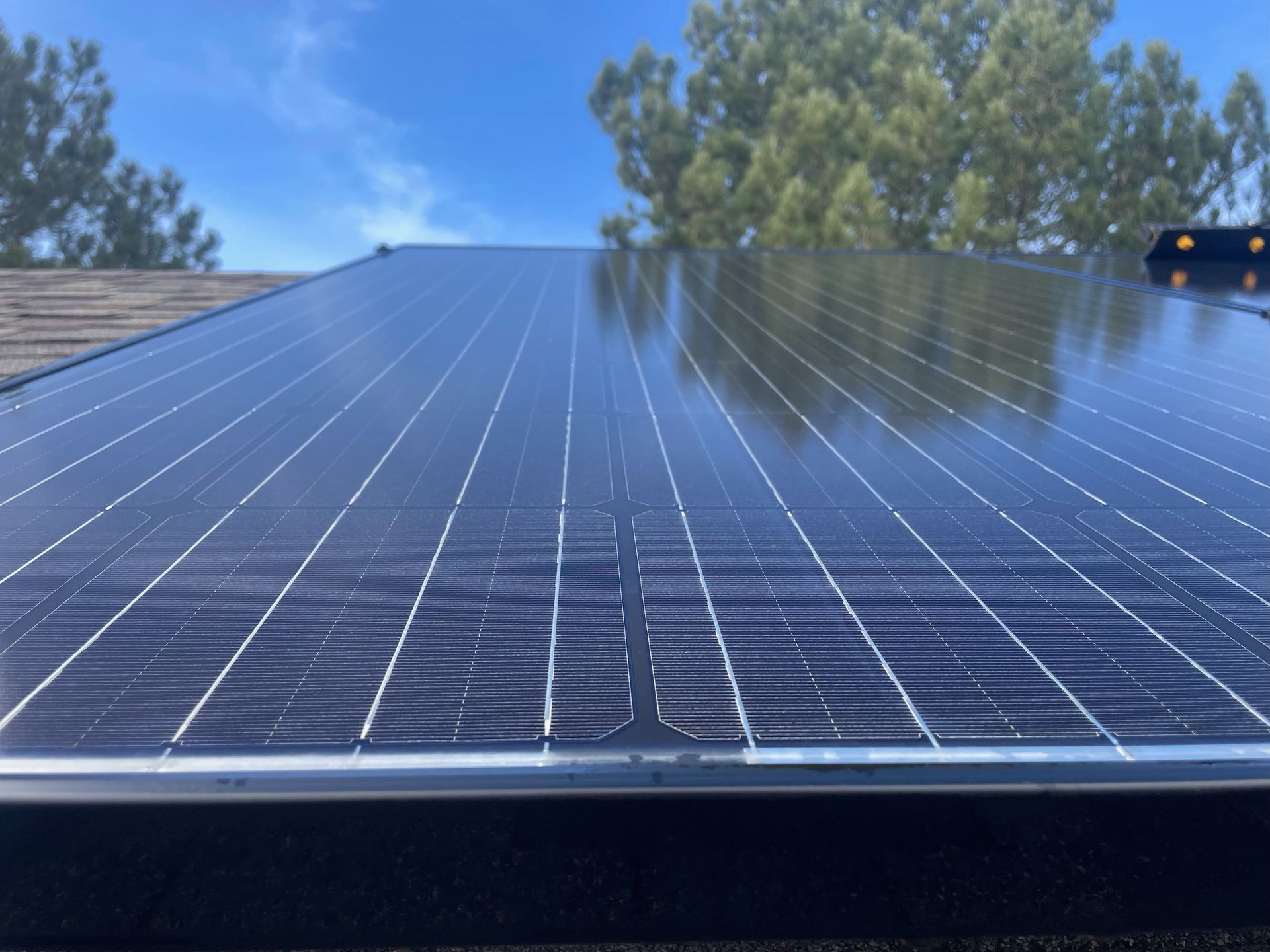 A close up of a solar panel on a roof with trees in the background.