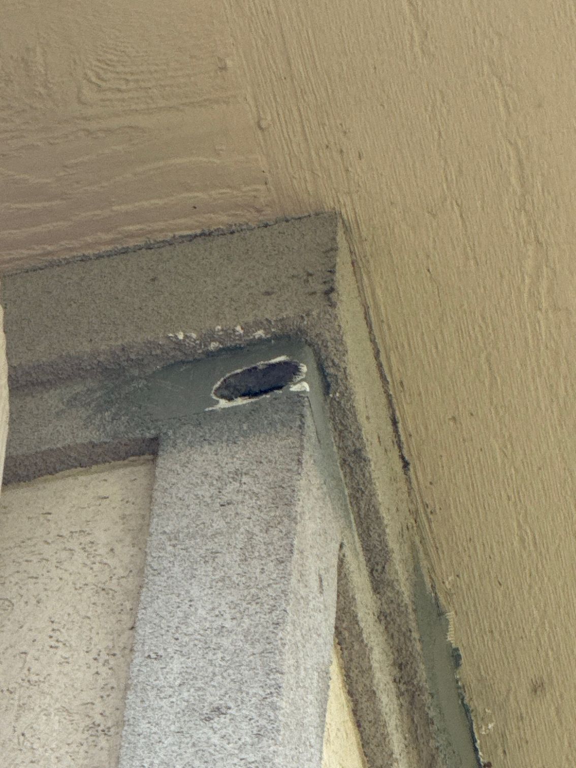 A close up of a corner of a wall with a hole in it.