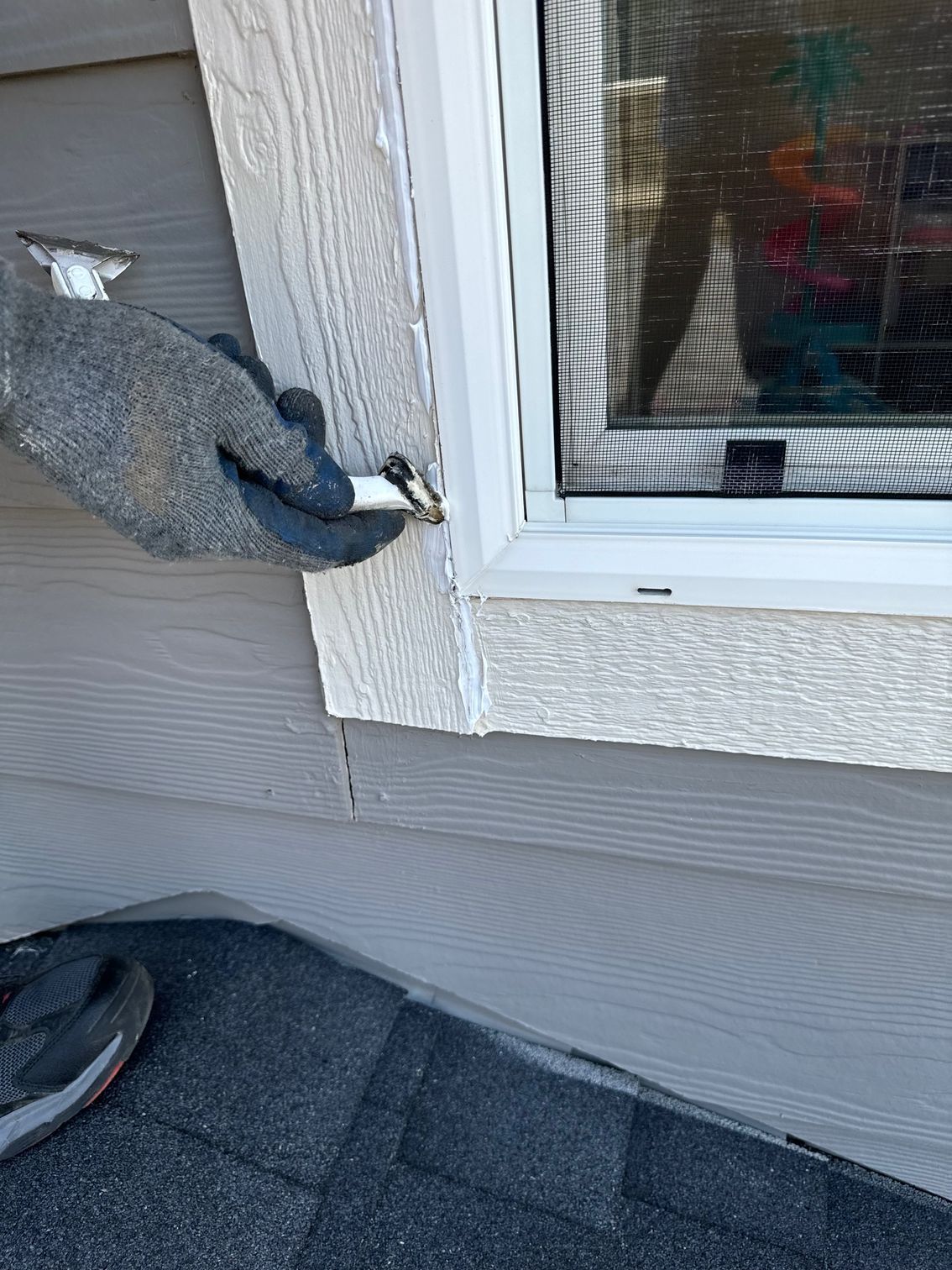 A person is fixing a window on the side of a house.