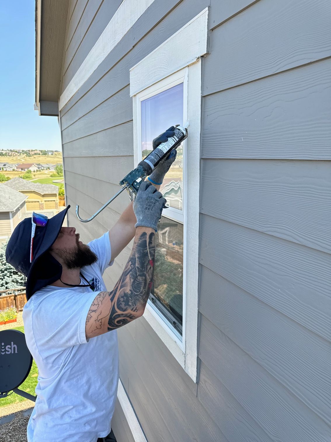 A man is installing a window on the side of a house.