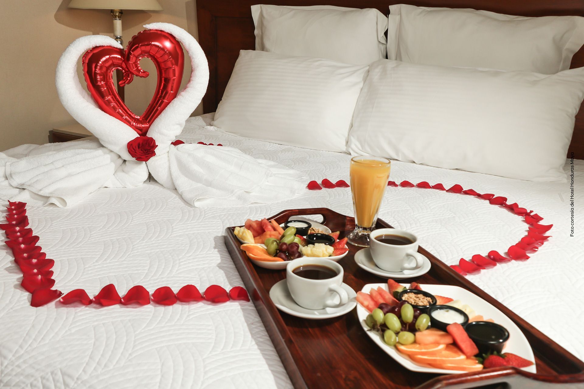una cama con una bandeja de comida y un globo en forma de corazón