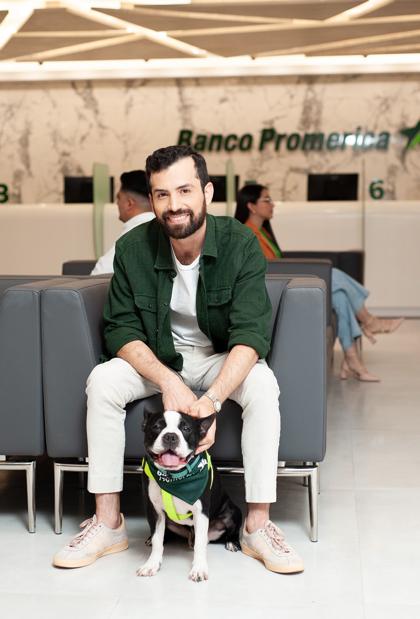 un hombre está sentado en un sofá con un perro dentro de Banco Promerica