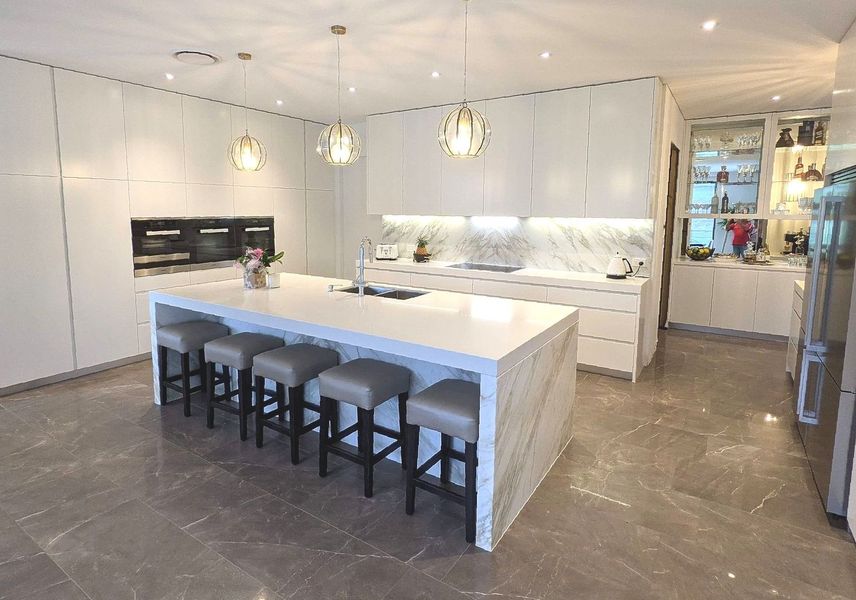 Modern White Kitchen With Island and Bar Stools — The Right Kitchen Company In Berkeley, NSW Modern White Kitchen With Island and Bar Stools — The Right Kitchen Company In Berkeley, NSW