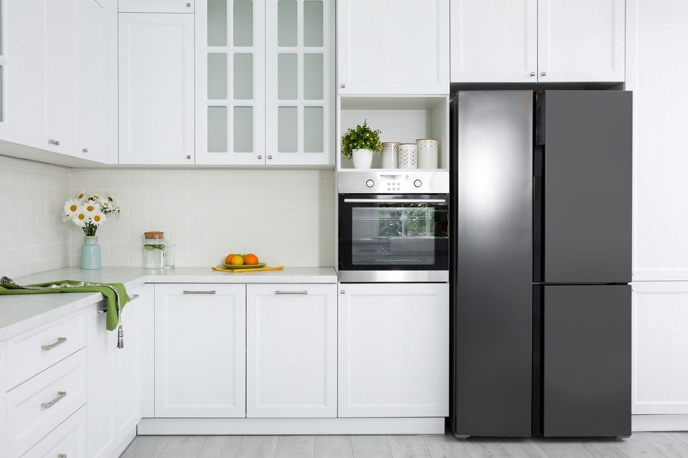 A Kitchen With White Cabinets And A Black Refrigerator — The Right Kitchen Company in Thirroul, NSW