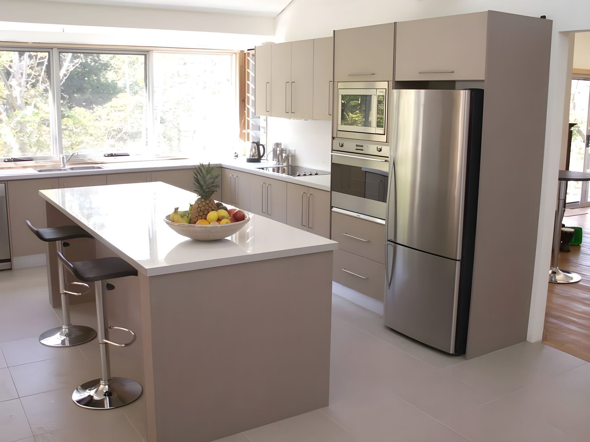 A light filled kitchen with a silver fridge  — The Right Kitchen Company In Berkeley, NSW
