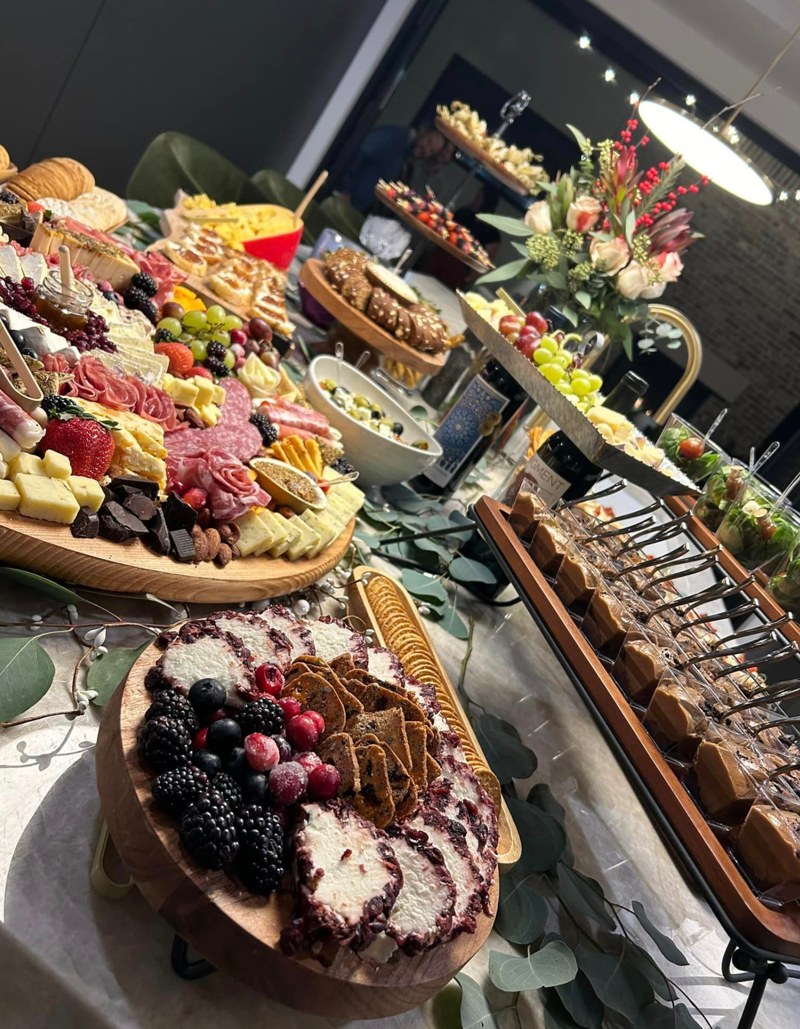 A wooden tray filled with fruits and meats on a table.