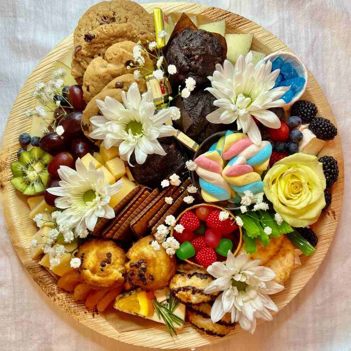 A wooden plate topped with a variety of food and flowers.