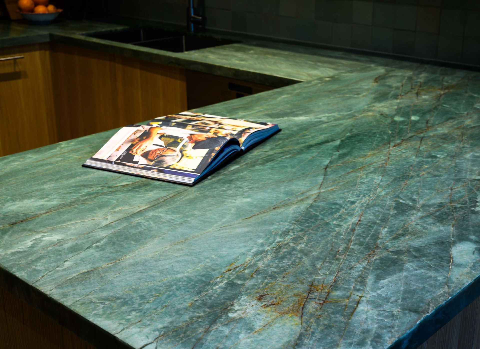 A book is sitting on a green counter top in a kitchen.