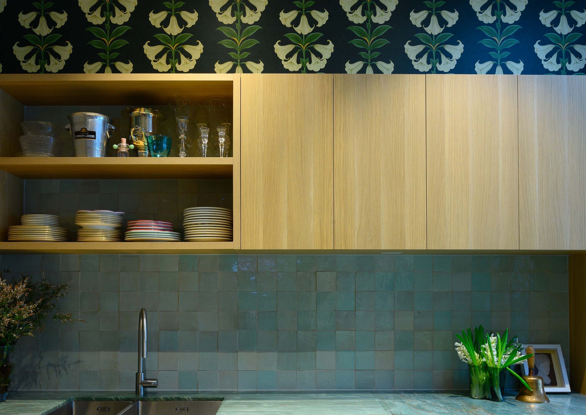 A kitchen with a sink and shelves filled with dishes.