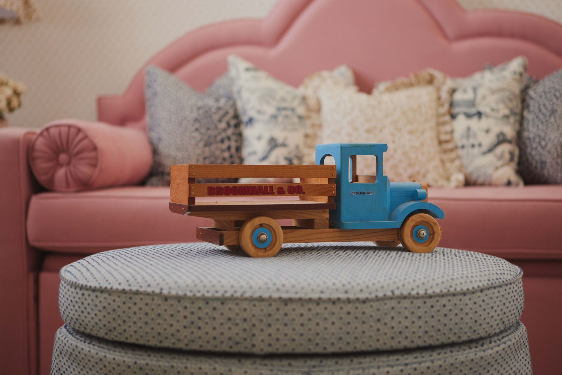 A toy truck is sitting on a table in front of a pink couch.