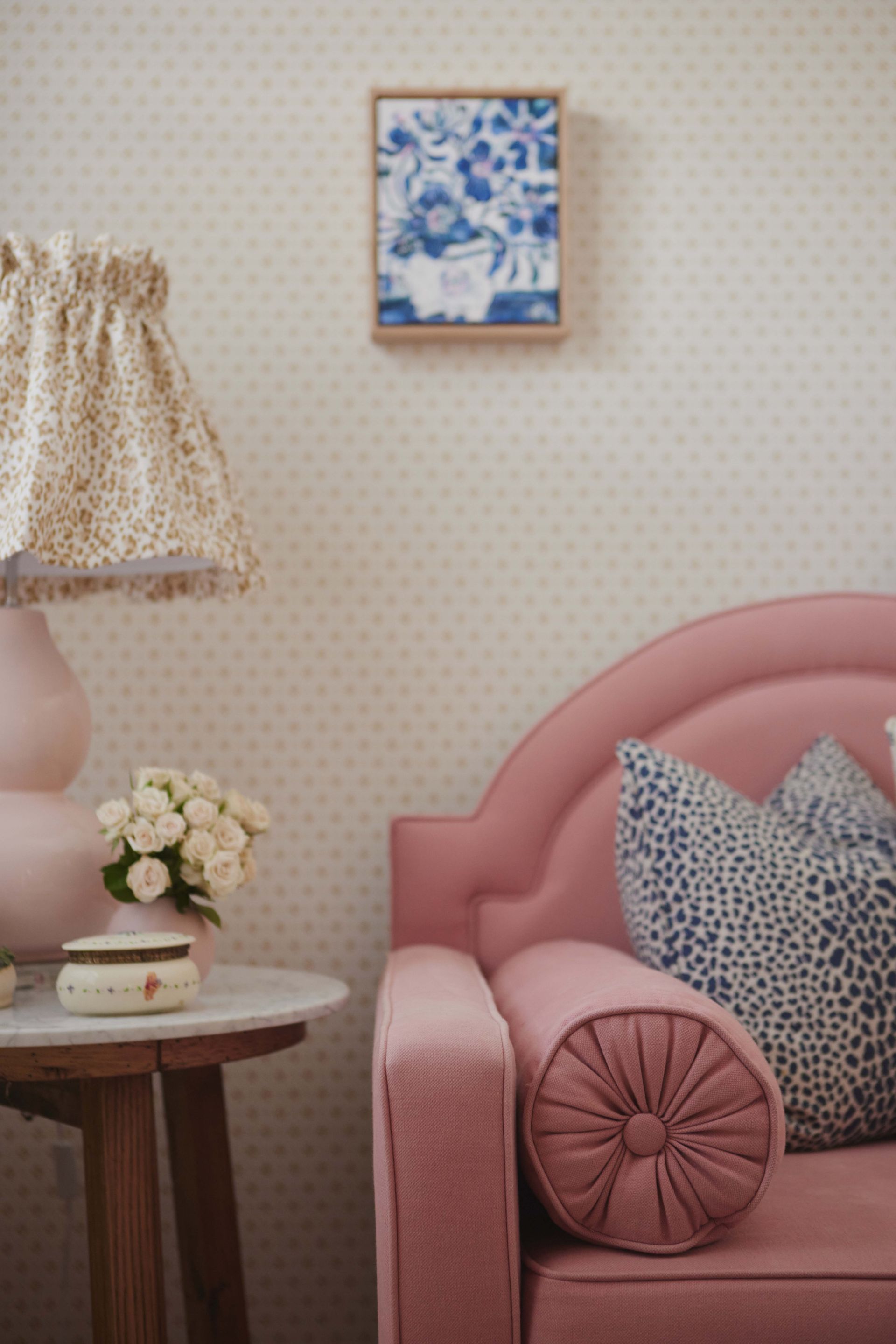 A living room with a pink couch and a lamp