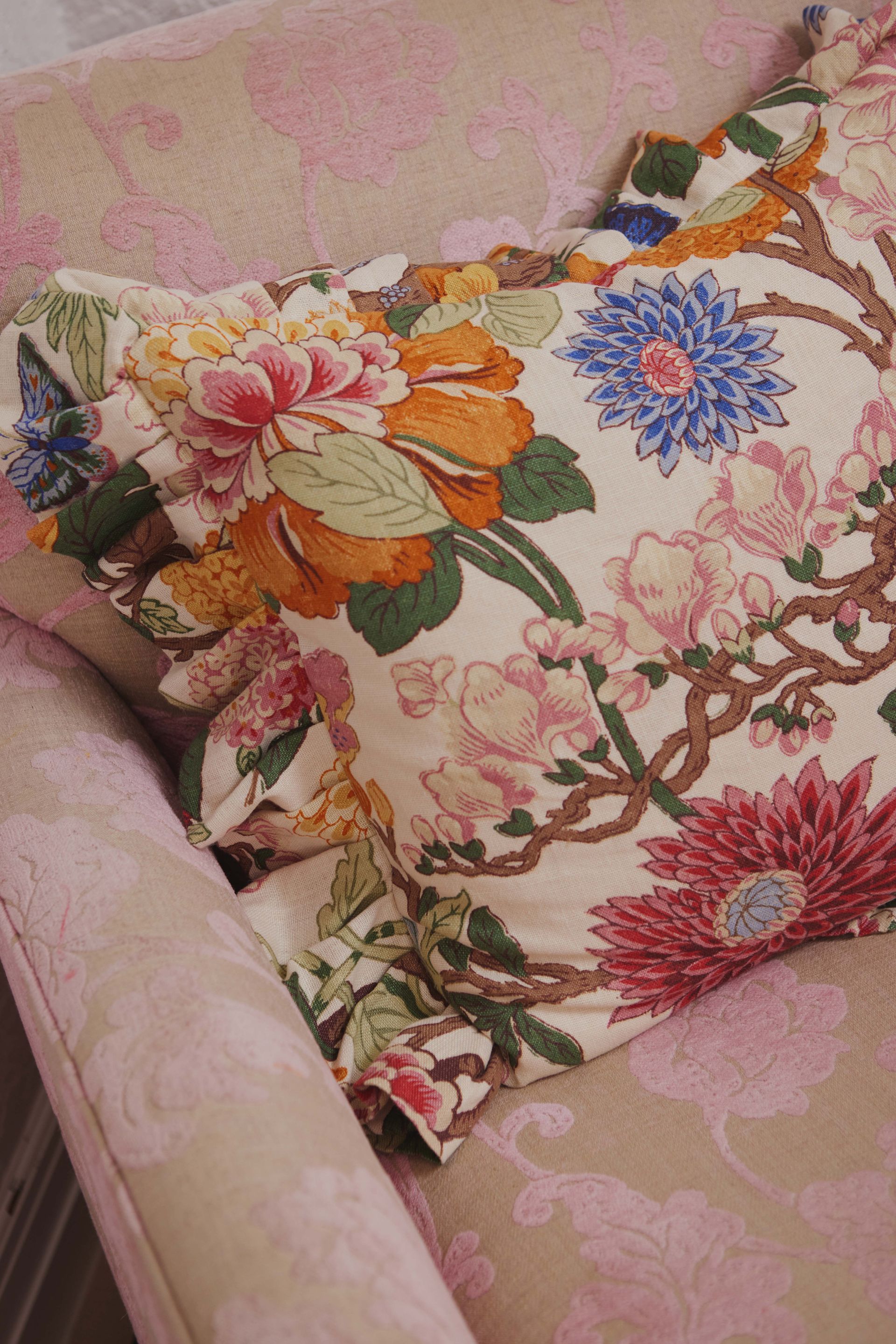 A pink chair with a floral pillow on it