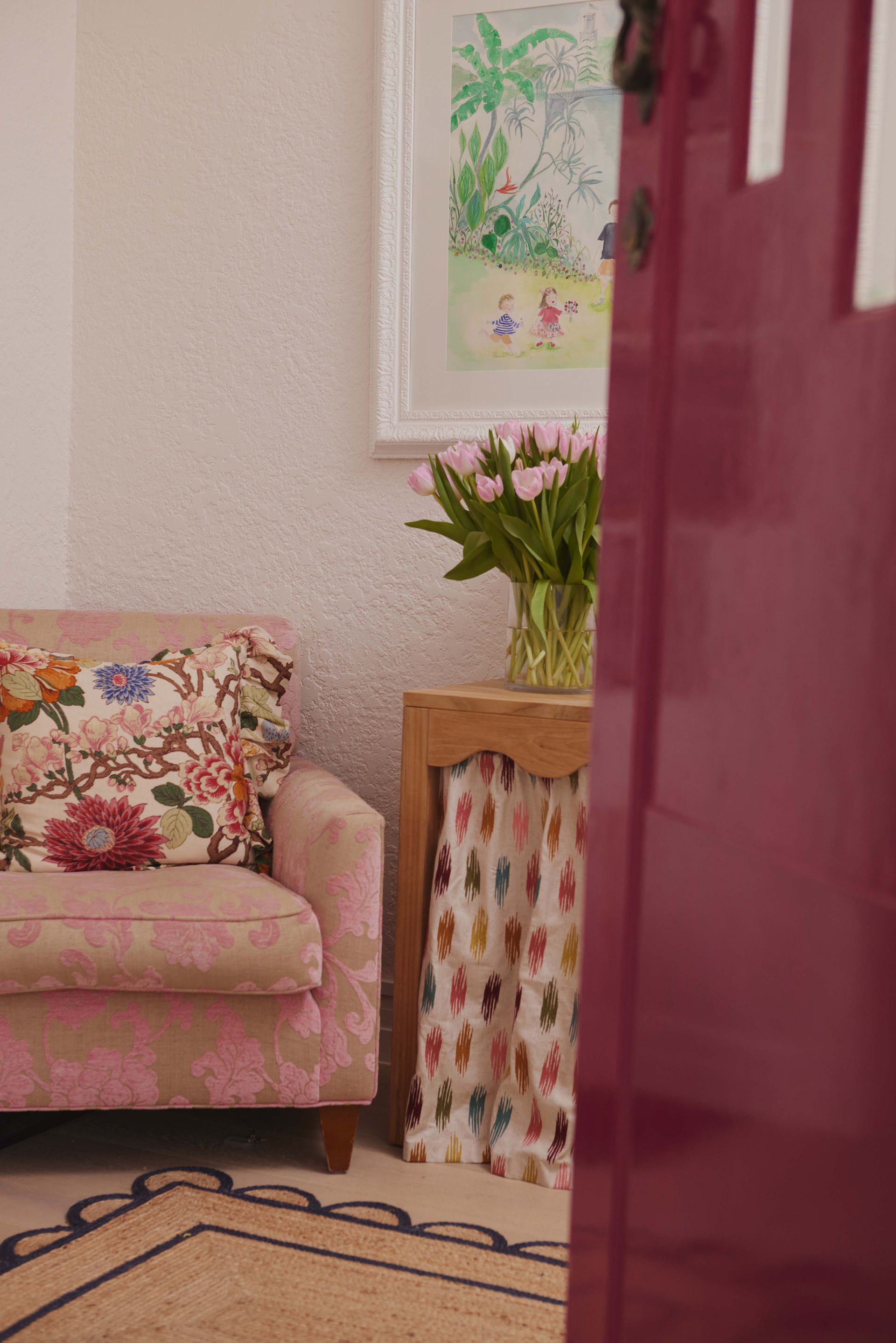 A living room with a pink couch and a red door.