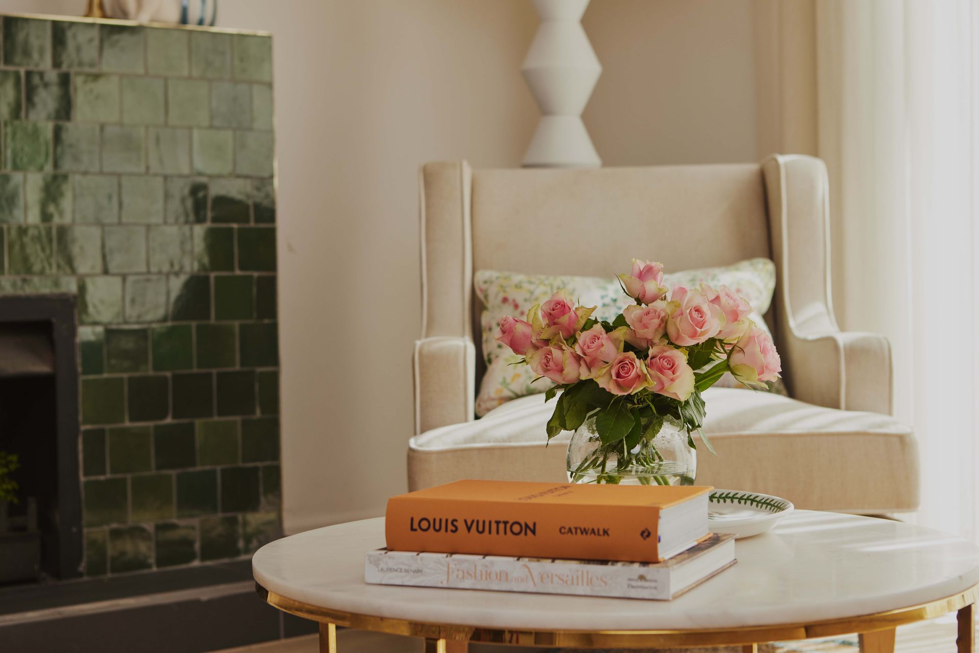 A living room with a chair and a table with a vase of flowers on it.