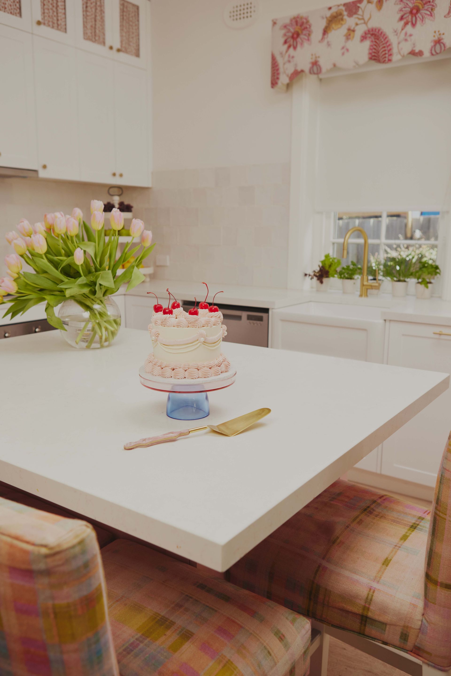 A cake is sitting on a table in a kitchen next to a vase of flowers.