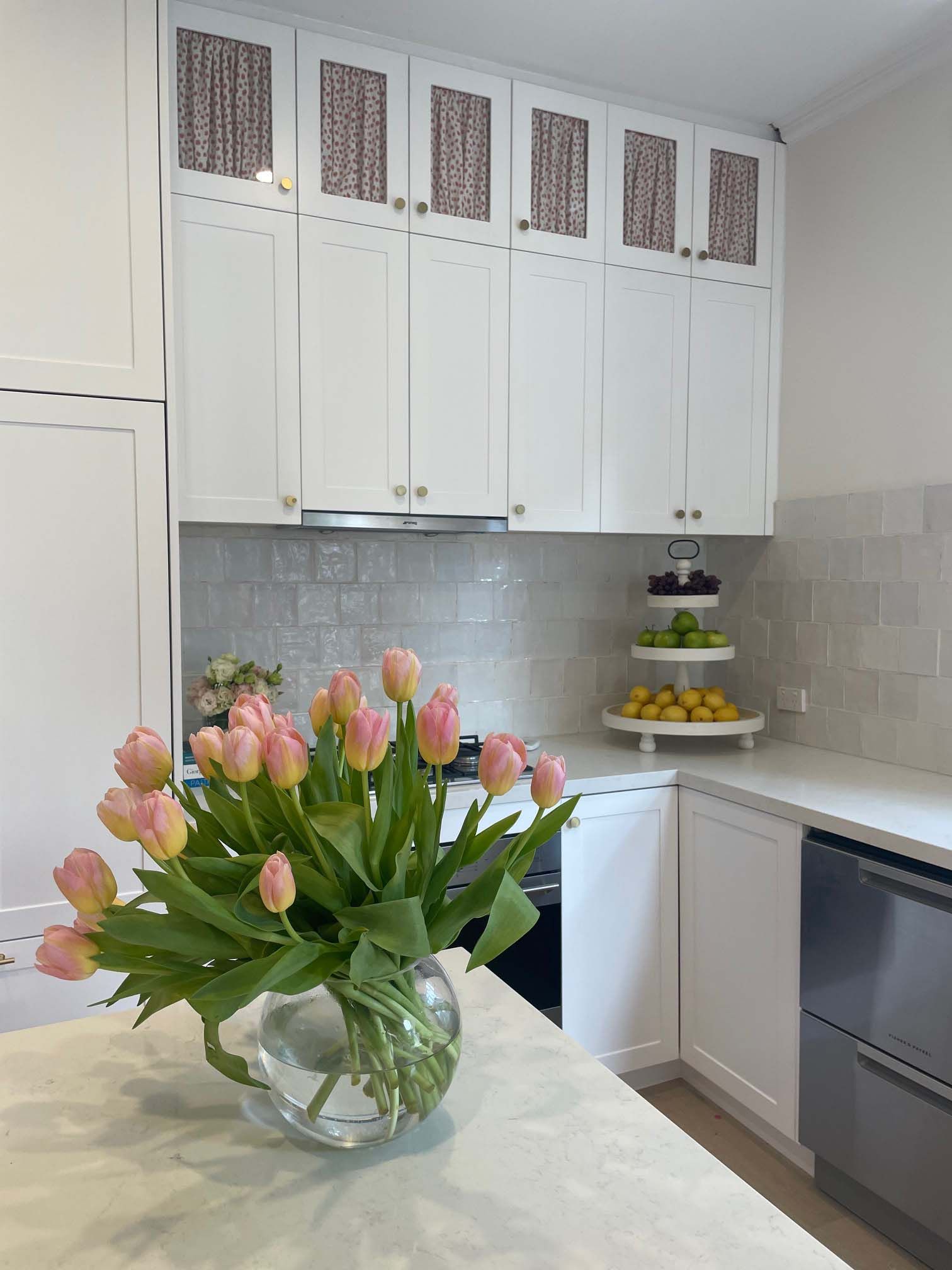 A vase of pink tulips is sitting on a kitchen counter.