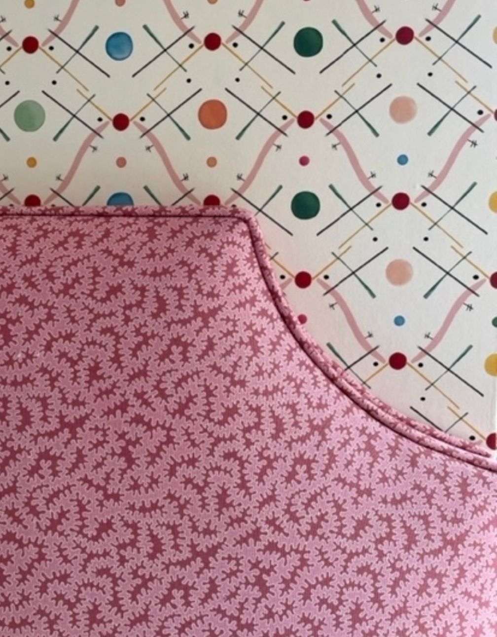 A living room with a red couch, lamp, table and hearts hanging from the ceiling.