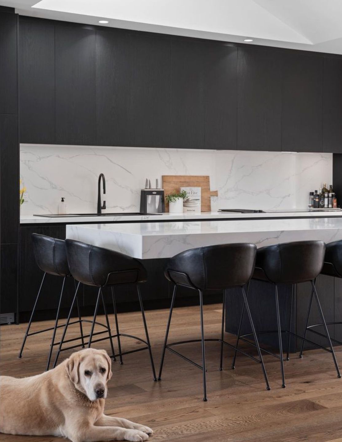 A dog is laying on the floor in a kitchen next to a table and chairs.