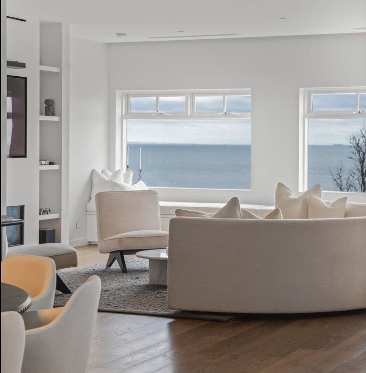 A living room with a couch and chairs with a view of the ocean