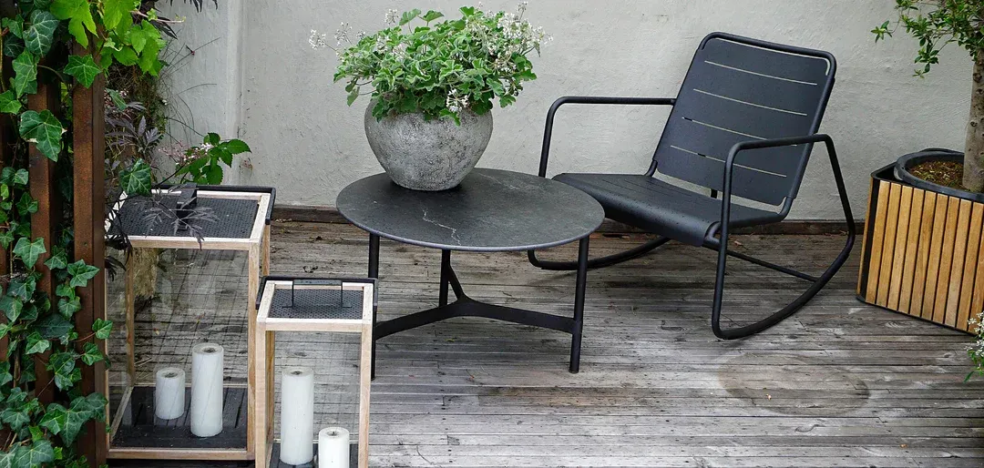 There is a rocking chair and a table on the deck.