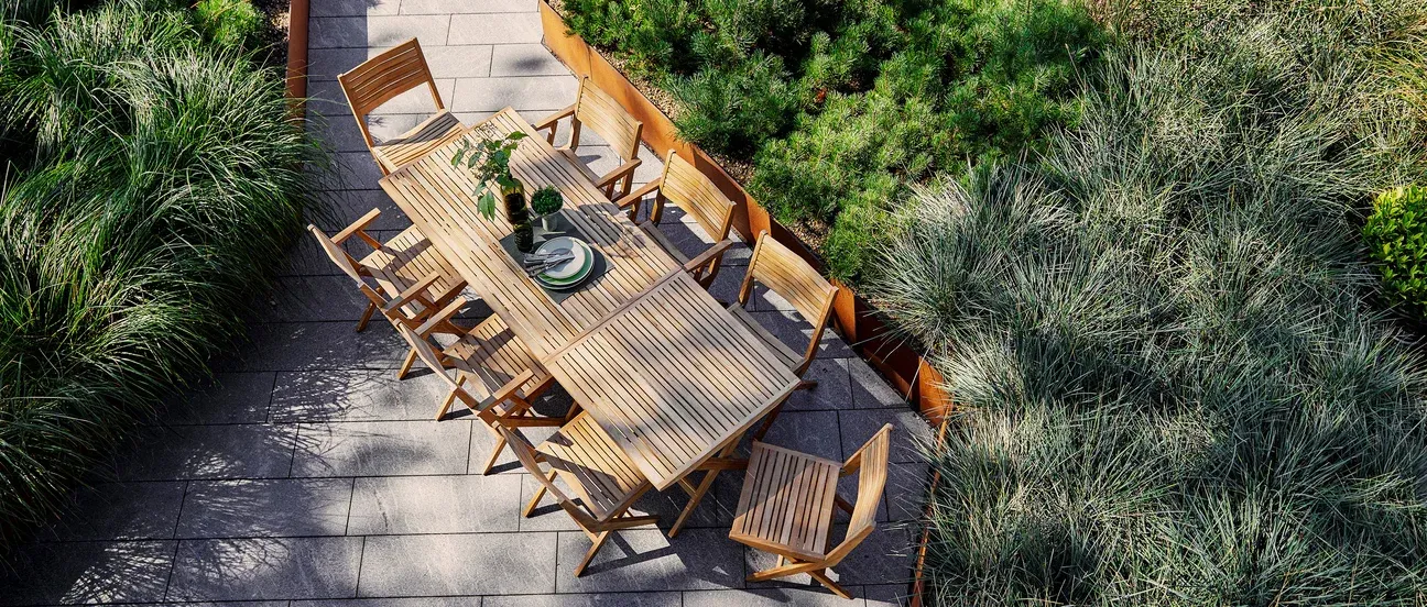 An aerial view of a wooden table and chairs on a patio.