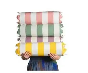 A person is holding a stack of striped pillows in front of their face.