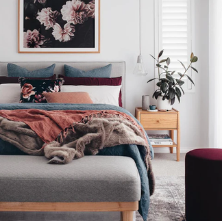 A bedroom with a bed and a picture on the wall above it
