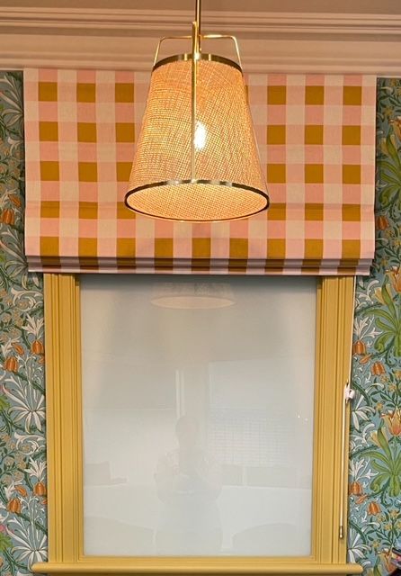 There is a lamp hanging from the ceiling above a window.