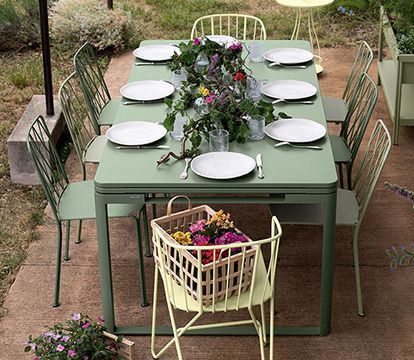 There is a basket of flowers on the chair next to the table.