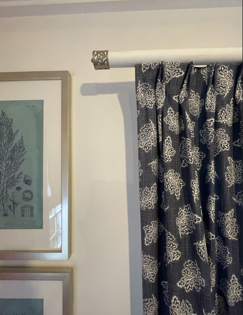 A curtain with a floral pattern hangs on a white pole