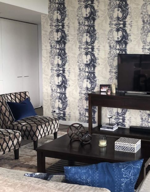 A living room with a white couch, chair, lamp and rug.
