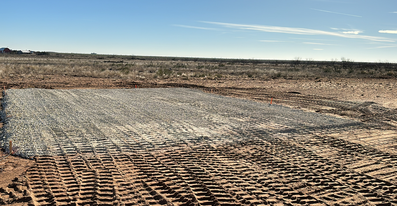 A large dirt field with a blue sky in the background.