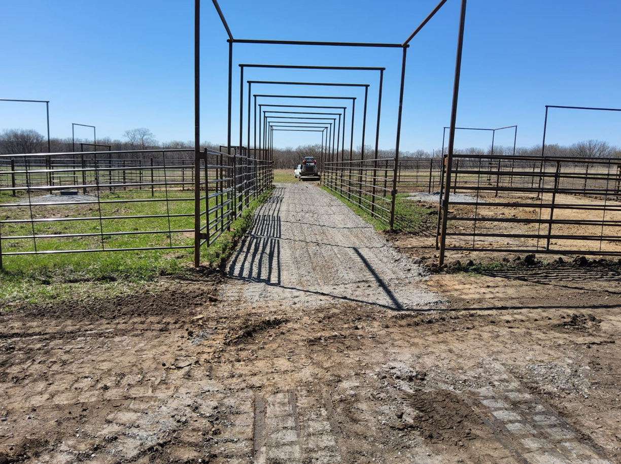 A dirt road going through a fenced in area