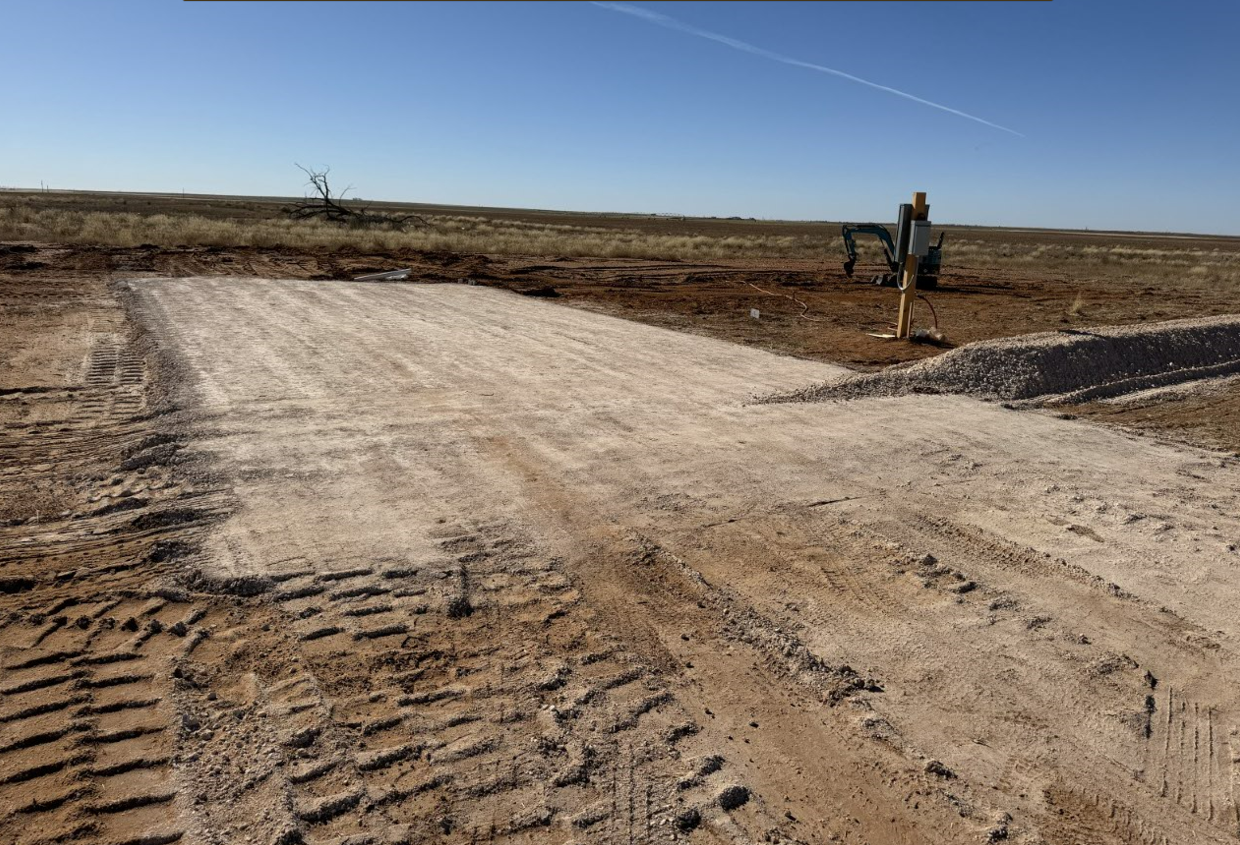 A dirt road is being built in the middle of a field.