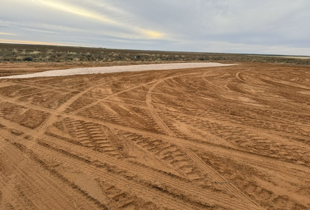 There are a lot of tire tracks in the dirt.