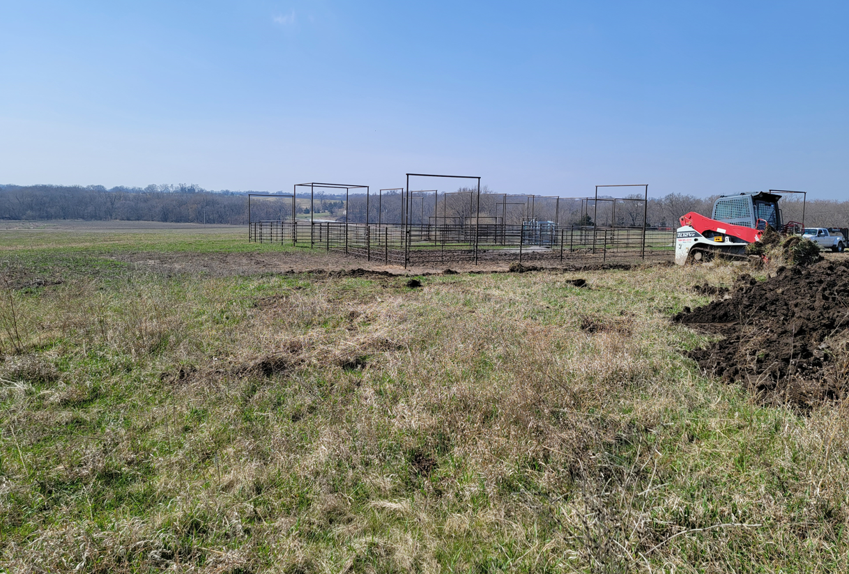 A tractor is plowing a field with a fence in the background.