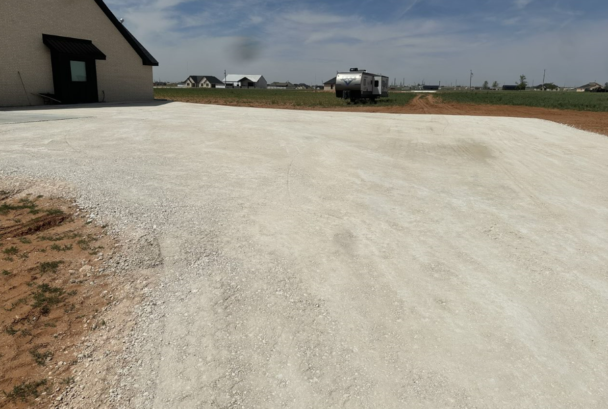 A gravel driveway with a house in the background