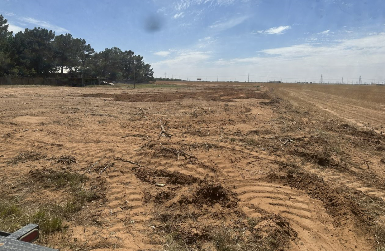 A large dirt field with a blue sky in the background.