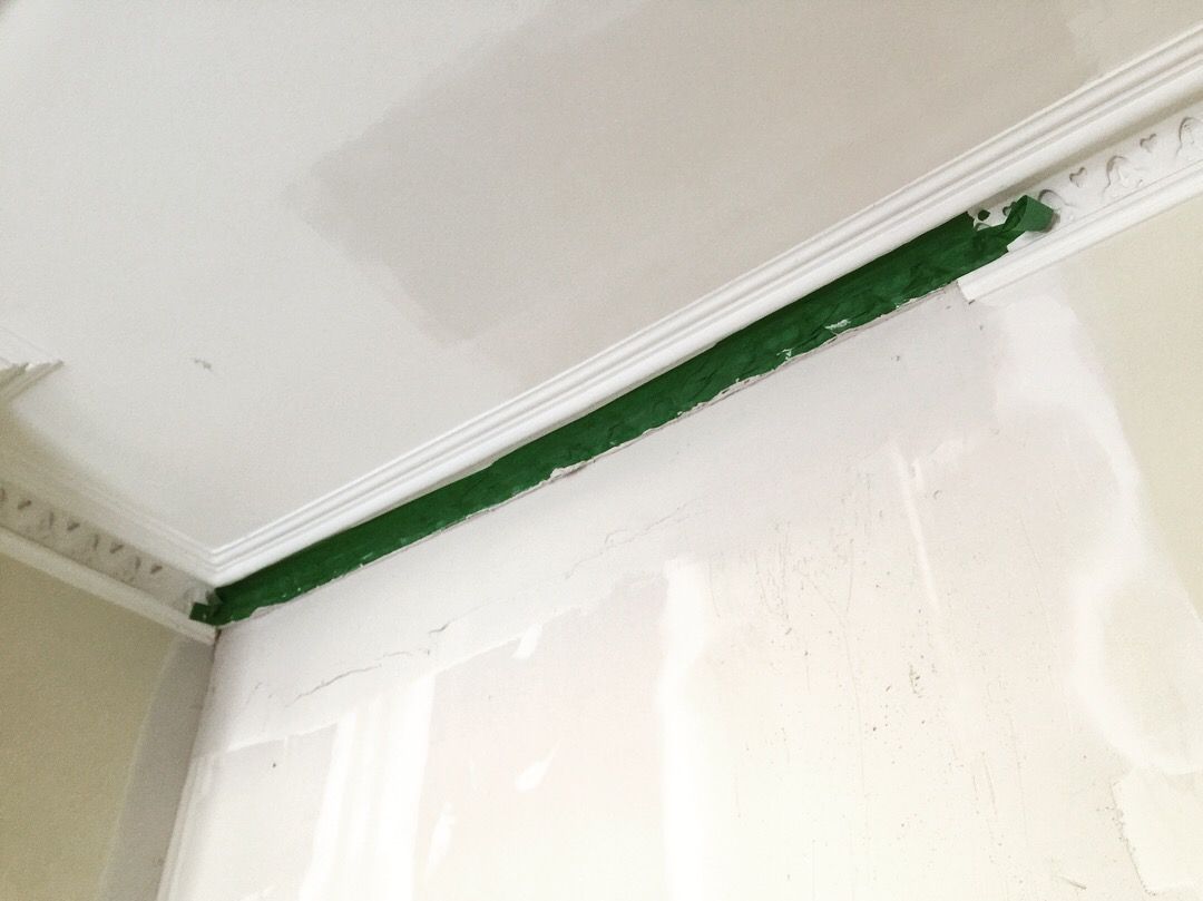 Une personne peint un coin d'un mur avec de la peinture verte.