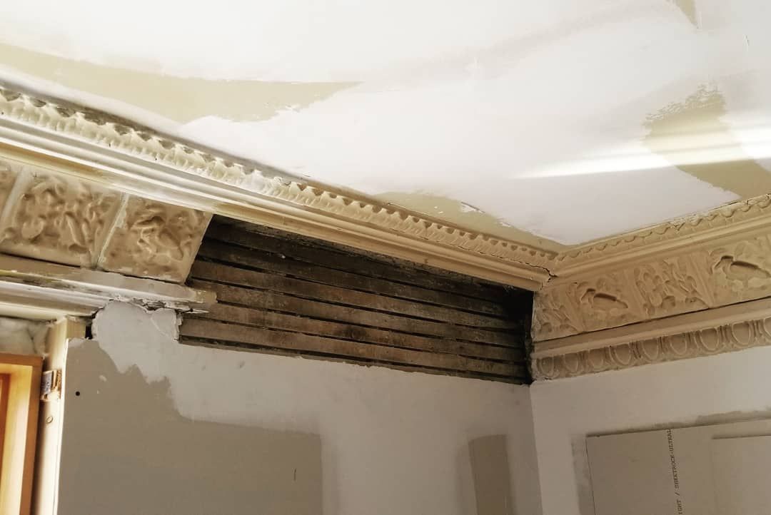Une pièce avec une moulure au plafond et un mur en briques.