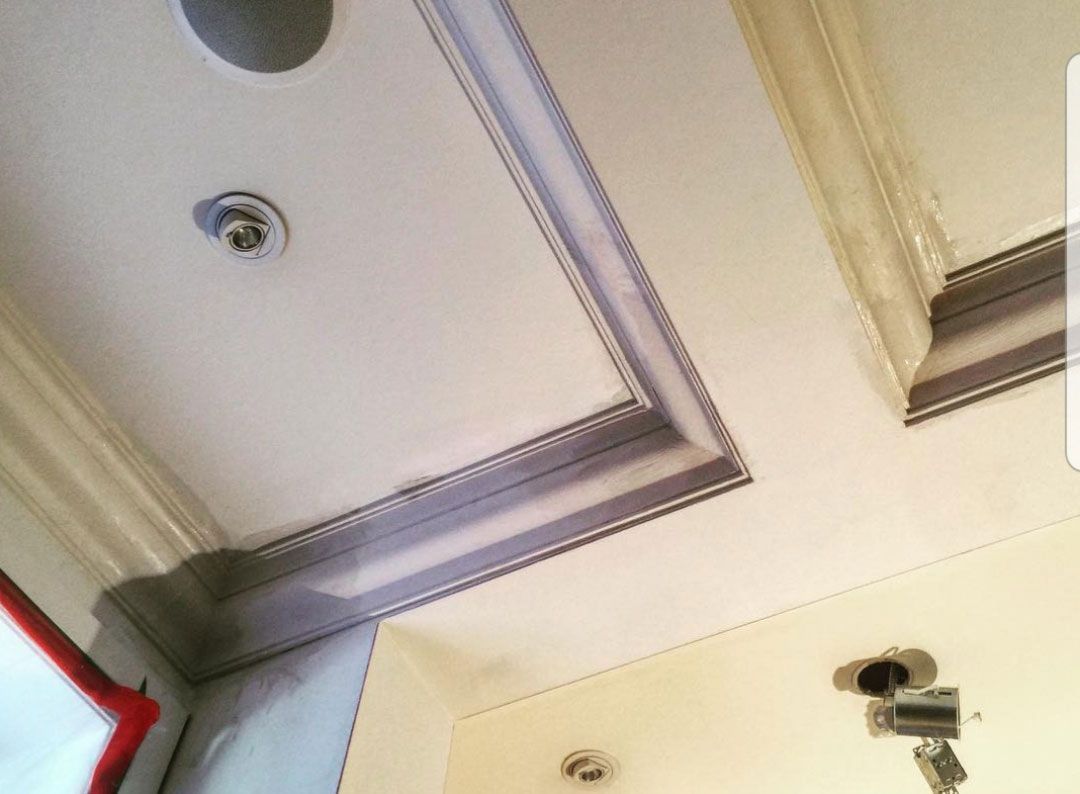 Un plafond avec une moulure et un détecteur de fumée dessus