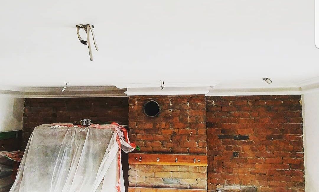 Une pièce avec un mur de briques et un plafond blanc.