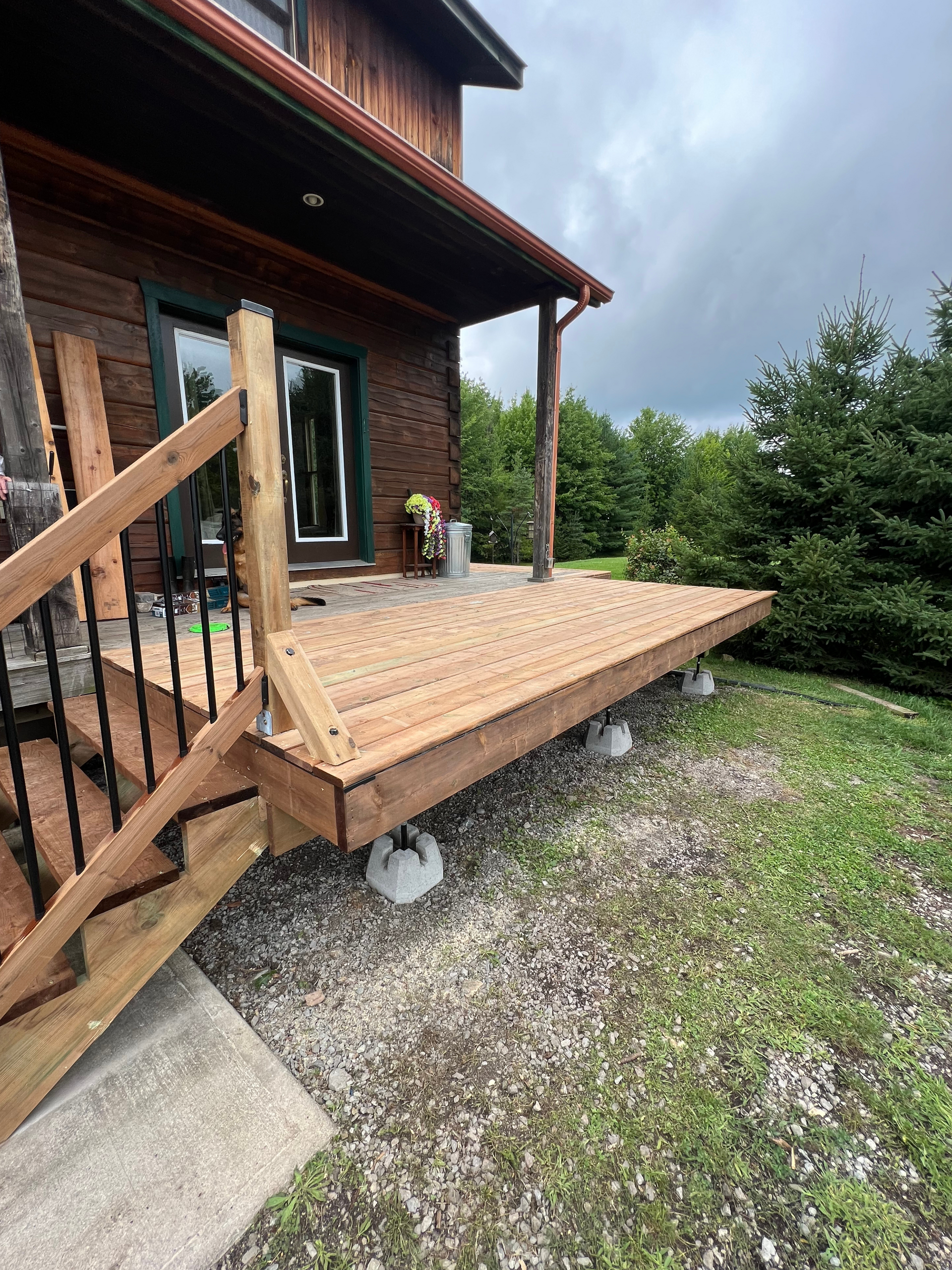 A wooden deck with stairs is being built in front of a house.